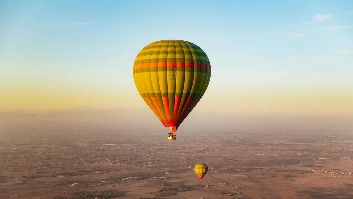 A hot air balloon flying over the Jbilet Mountains desert landscape on a hot air balloon ride in Marrakech, Morocco