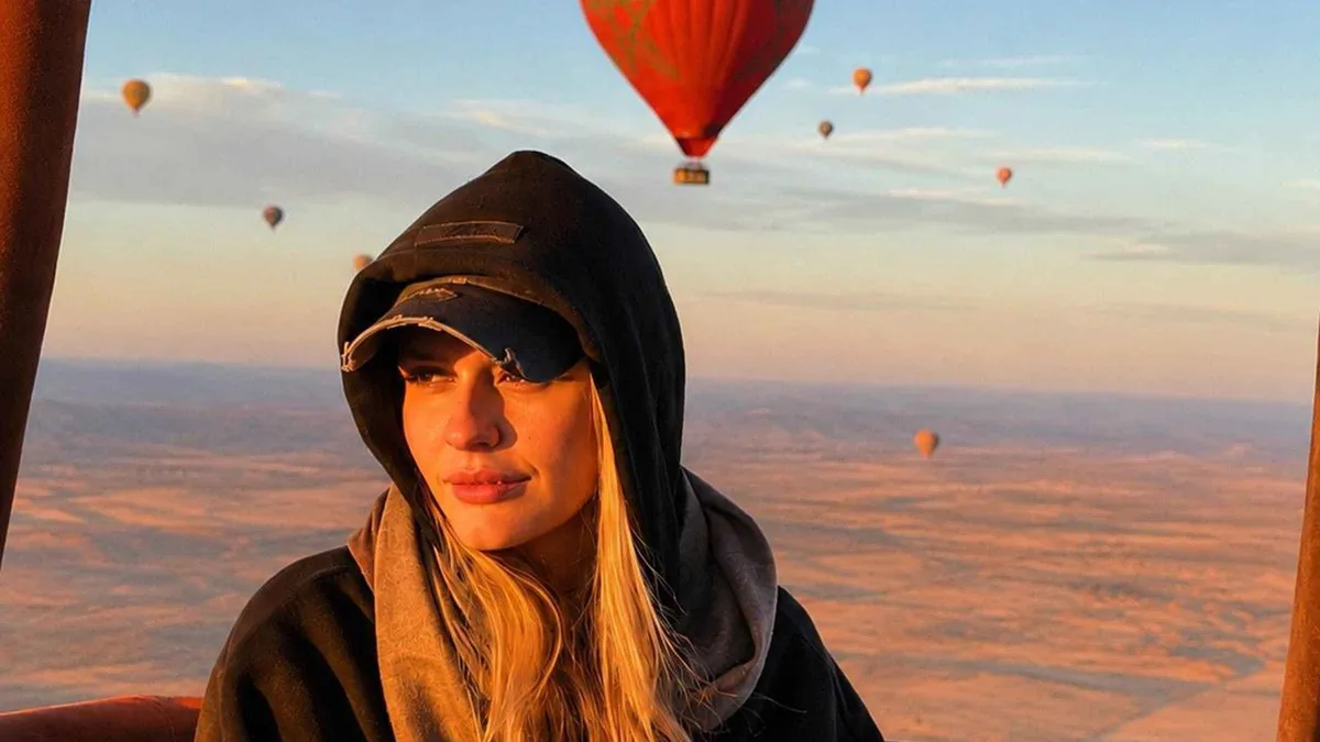 A hot air balloon lit by sunrise over ochre desert terrain on a hot air balloon ride in Marrakech, Morocco